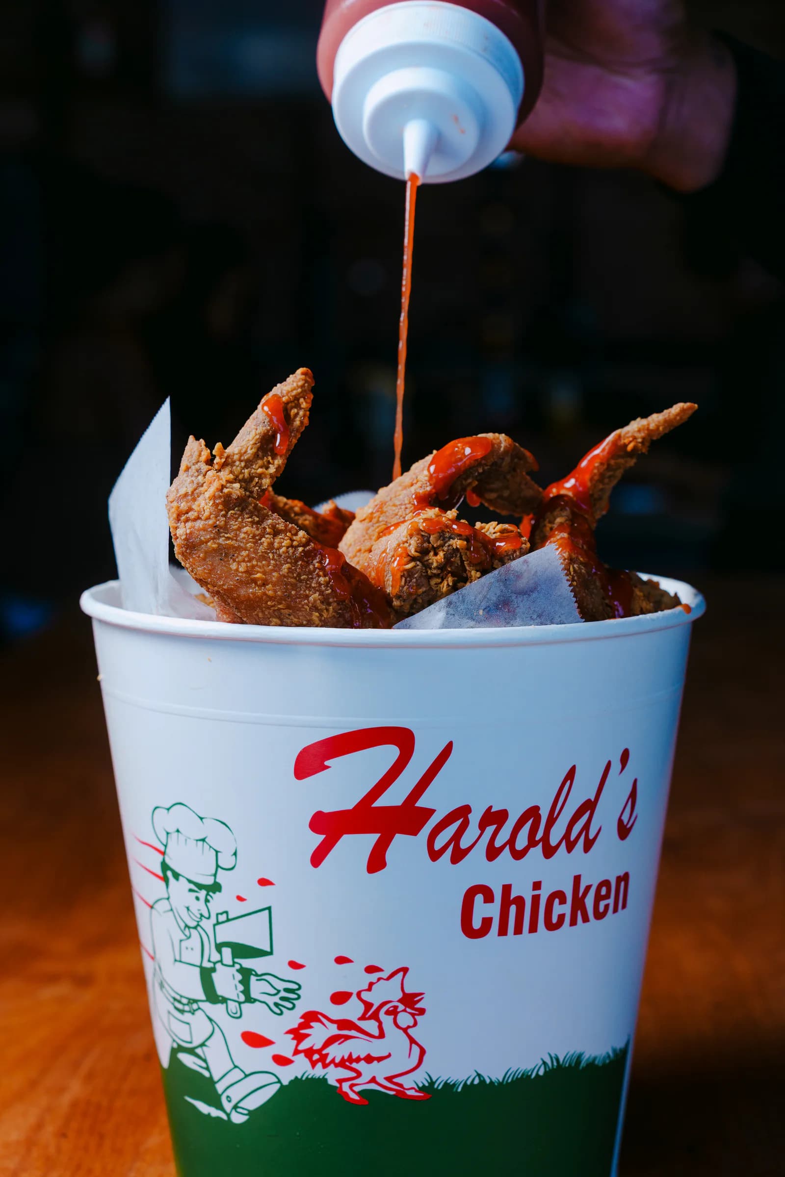 Hot sauce being poured over Harold's fried chicken wings